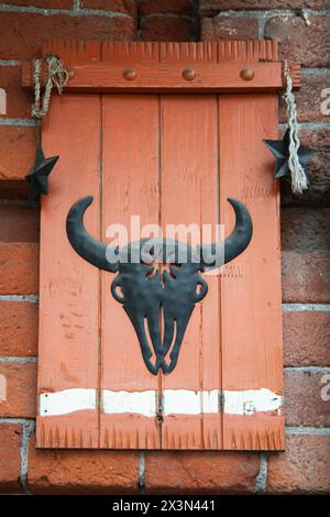 Vertikaler Schuss von Metall-Bullkopf auf Holzoberfläche. Fleischgeschäft-Konzept Stockfoto