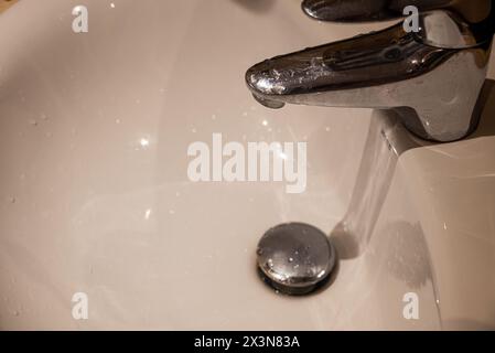 Nahaufnahme des Waschbeckens im Bad mit fließendem Wasser aus dem Wasserhahn Stockfoto