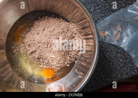 Eier mit Öl und Cupcake vermischen Pulver in einer Metallschale für ein leckeres Rezept. Stockfoto