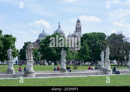 Sonniger Tag im Prato della Valle mit Menschen am Kanalufer. Die zentrale grüne Insel Memia, umgeben von Statuen. Im Blick auf die Abteibasilika von Sa Stockfoto