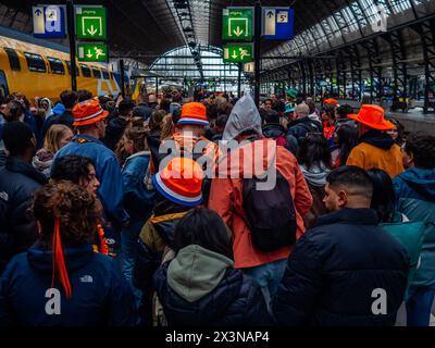 Amsterdam, Niederlande. April 2024. Man sieht Menschen, die am Hauptbahnhof ankommen. Der Königstag ist bekannt als eines der größten und farbenprächtigsten Festlichkeiten des Landes, besonders in Amsterdam. Die Stadt strotzt vor Orange, während die Menschen die größte Straßenparty des Jahres genießen, die freien Märkte genießen und Spaß auf den Booten entlang der Kanäle haben. Quelle: SOPA Images Limited/Alamy Live News Stockfoto