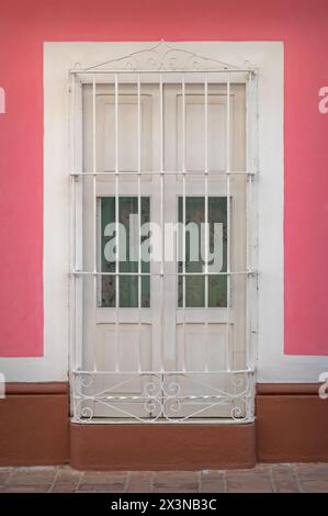 Hell bemalte Wände und Metallgitter über Fenstern älterer Häuser in den Seitenstraßen von Trinidad, Kuba. Stockfoto