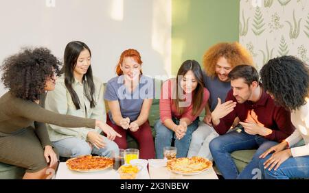 Multirassische Gruppe glücklicher Freunde, die Pizza zu Hause essen Stockfoto