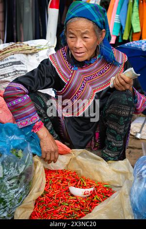 Schwarze Hmong-Frau verkauft Chilis auf dem Cau-Markt in Lao Cai, Vietnam Stockfoto