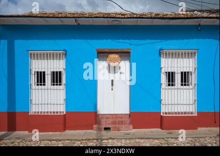 Hell bemalte Wände und Metallgitter über Fenstern älterer Häuser in den Seitenstraßen von Trinidad, Kuba. Stockfoto