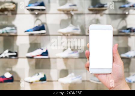 Handgriff Handy mit Sportschuhen in Regalen im Schuhspeicher Unschärfe für den Hintergrund Stockfoto