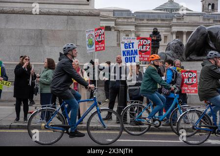 London, Großbritannien. April 2024. Radfahrer fahren an den Demonstranten auf dem Trafalgar Square in London vorbei. ULEZ steht für Ultra Low Emission Zone. Sie wurde im April 2019 eingeführt, um eine sauberere Luft in London zu erzeugen. Die Erweiterung erfolgte Ende August 2023. Jetzt deckt die ULEZ den Großteil des Grundstücks innerhalb der M25 ab. Die Demonstranten geben Sadiq Khan, dem Bürgermeister von London, die Schuld und glauben nicht an die Luftverschmutzung. (Foto: Krisztian Elek/SOPA Images/SIPA USA) Credit: SIPA USA/Alamy Live News Stockfoto