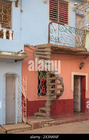 Die Vorderseite einiger Hotels mit einer unglaublich schmalen Tür und einer spiralförmigen Außentreppe ohne Geländer in einem alten Teil von Trinidad, Kuba Stockfoto