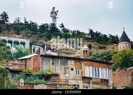 Verfallene alte Häuser in der Altstadt von Tiflis (Kala) mit der Statue der Mutter von Georgien (Kartlis Deda) im Hintergrund Stockfoto