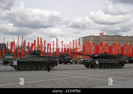 28. April 2024, Russland, Moskau: Ein deutscher Kampfpanzer Leopard 2, der nach russischen Quellen in der Ukraine gefangen genommen wurde, und ein Marder (links) stehen bei einer Ausstellung von Kriegstrophäen im Pobedy Park (Park des Sieges). Im Hintergrund sind rote Fahnen mit der Inschrift Pobeda! (Auf Deutsch: Sieg). Am 9. Mai feiert Russland den Tag des Sieges der Sowjetunion über Nazi-Deutschland im Zweiten Weltkrieg. Die neue Ausstellung im Park ist der russischen Offensive gegen die Ukraine gewidmet, die seit mehr als zwei Jahren andauert und soll den Willen Moskaus zum Sieg unterstreichen. Foto: Ulf Maud Stockfoto