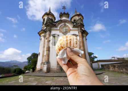 Pao de queijo (brasilianisches Käsebrötchen) mit der Kirche St. Franz von Assisi in Ouro Preto, Minas Gerais, Brasilien, ist die Stadt Weltkulturerbe von Stockfoto