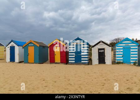 Alte Strandhütten, die nach berühmten Menschen und Monarchen benannt sind, mit Sanddünen am Southwold Denes Beach, Southwold, Suffolk, Großbritannien im April Stockfoto