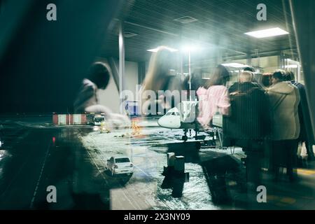 Reflexion im Fenster auf Fluggäste und ihr Gepäck, die entlang des Fluggastkorridors des Flugzeugs vom Terminal zum Flugzeug laufen. Hochwertige Fotos Stockfoto