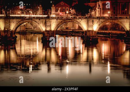 Die Lichter der Brücke Ponte Vittorio Emanuele II spiegeln sich im Fluss Tibor, während er durch Rom fließt. Stockfoto