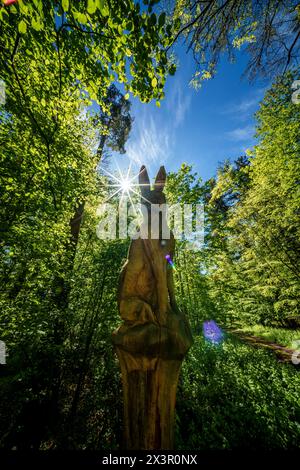 Eine Skulptur steht auf einer Waldlichtung, in der das Sonnenlicht durch die Bäume filtert und die komplizierten Details hervorhebt. Die natürliche Landschaft ist umgeben Stockfoto