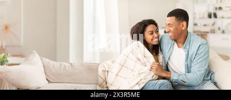 Paare kuscheln sich zu Hause auf der Couch mit Decke Stockfoto