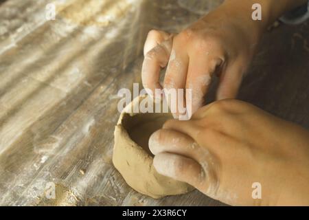 Eine Frau formt eine graue Tonplatte mit ihren Händen, Nahaufnahme. Basteln aus Lehm. Hobbys und Kreativität. Stockfoto