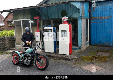 Motorradfahrer auf einem maßgeschneiderten Motorrad in einer alten, stillgelegten Garage in Lost Wenlock, Shropshire Stockfoto