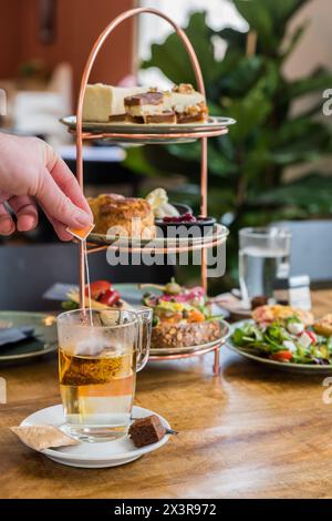 Traditioneller englischer Nachmittagstee mit einer Mischung aus süßen und herzhaften Snacks und Häppchen auf einem Tisch in einem Bäckereicafé Stockfoto