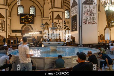 Bursa, Türkei - 13. April 2024: Blick auf das Innere der Großen Moschee und Muslime, die im Brunnen abwässern Stockfoto