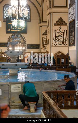 Bursa, Türkei - 13. April 2024: Blick auf das Innere der Großen Moschee und Muslime, die im Brunnen abwässern Stockfoto