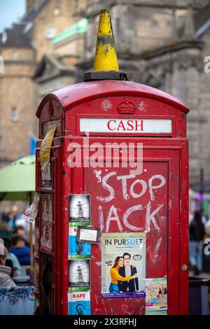 Ein ehemaliger Telefonkiosk auf der Royal Mile von Edinburgh, mit Plakaten und Graffiti Stockfoto