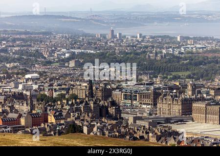 Vom Arthur’s Seat aus hat man einen Blick über Edinburgh, die Princes Street verläuft im Vordergrund und die Forth Bridges in der Ferne Stockfoto