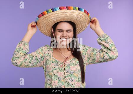Junge Frau mit mexikanischem Sombrero-Hut auf violettem Hintergrund Stockfoto