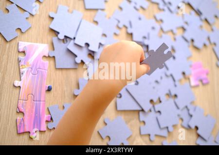 Das kleine Kind baut Puzzles zusammen, sortiert Pappstücke nach Form, Lernspielzeug und Spiele, kognitive Entwicklung des Kindes durch Puzzle-Solvi Stockfoto