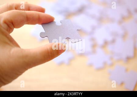 Weibliche Hand hält Papppuzzlespiel, logische Fähigkeiten, Puzzlespiel lösen und Gedächtnisverbesserung, Geschäftskonzept zum Vervollständigen Stockfoto