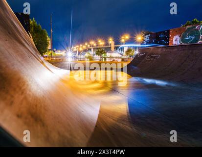 Wiesbaden, Deutschland. April 2024. Das Licht der Theodor-Heuss-Brücke, beleuchtet bei Nacht, wird auf den Bodenplatten einer Halfpipe reflektiert. Die Halfpipe befindet sich im Stadtteil Mainz-Kastel in Wiesbaden am Rheinufer. Darlegung: Andreas Arnold/dpa/Alamy Live News Stockfoto