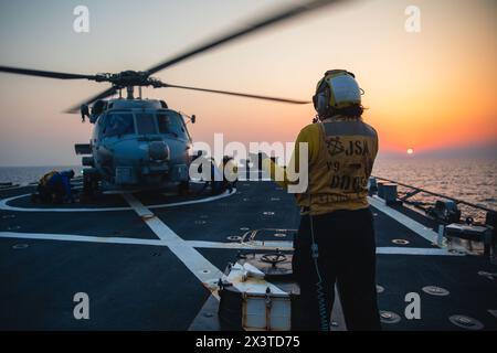 240418-N-PA221-2117 GOLF VON OMAN (18. April 2024) Ein Boatswain's Mate signalisiert, Keile und Ketten von einem MH-60R Sea Hawk Hubschrauber zu entfernen, der der Helicopter Maritime Strike Squadron 74 zugewiesen ist, während des Flugbetriebs an Bord des Lenkraketenzerstörers der Arleigh-Burke-Klasse USS John S. McCain (DDG 56) im Golf von Oman, April. John S. McCain wird im Einsatzgebiet der 5. US-Flotte eingesetzt, um die Sicherheit und Stabilität im Nahen Osten zu unterstützen. (Offizielles Foto der US Navy) Stockfoto