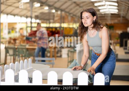 Mädchenkäufer wählen Tisch Schreibtisch im Gartenmöbelgeschäft Showroom Stockfoto