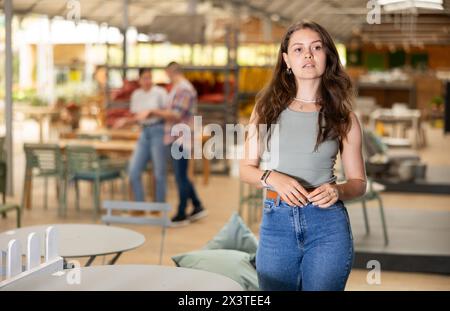 Mädchenkäufer wählen Tisch Schreibtisch im Gartenmöbelgeschäft Showroom Stockfoto