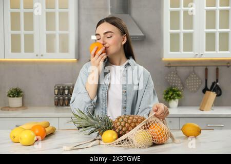 Frau mit Schnur mit frischem Obst am hellen Marmortisch in der Küche Stockfoto