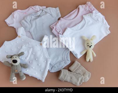 Set mit pinkfarbenen Kleidern und Accessoires für Neugeborene. Strickspielzeug Hase und Hund, Strampler, Socken und Handband. Babyduschkonzept. Flach liegend, Top-Wette Stockfoto