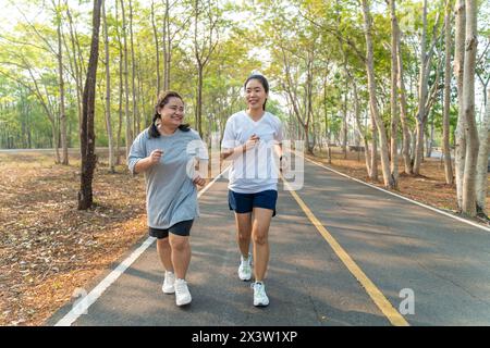 Zwei glückliche asiatische Freundinnen, die am Morgen zusammen in einem Laufpark an einem Sommertag laufen Stockfoto