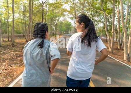 Rückansicht von zwei jungen Frauen, die gemeinsam in einem Park am Morgen laufen Stockfoto