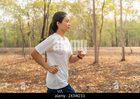 Junge Frau, die im Sommer alleine am Morgen im örtlichen Laufpark läuft Stockfoto