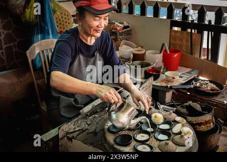 Vietnamesische Mini-Spiegeleier mit Reismehl. Asiatische Frau, die auf der Straße ein traditionelles vietnamesisches Frühstück zubereitet. Banh Dose ist ein beliebtes Gericht in der CE Stockfoto