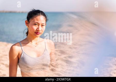 Junge besinnliche asiatische Frau am Strand Stockfoto