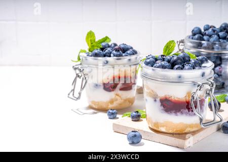 Mehrschichtiges Blaubeerparfait-Dessert, Käsekuchen im Glas mit Vanillekekuchen, cremiger Joghurt, Marmelade und frischer Blaubeere Stockfoto