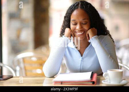 Vorderansicht Porträt eines glücklichen schwarzen Schülers, der Notizen auf einer Bar-Terrasse auswendig macht Stockfoto