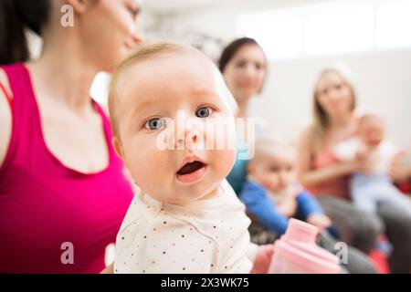 Bewegungsklasse für Babys. Eltern helfen Babys, die motorischen Fähigkeiten zu verbessern, die richtige Bewegung auf dem Fitball. Pädiatrie Physiotherapeut in der Spitzenklasse. Mütter Stockfoto