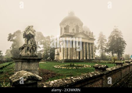Nebelansicht der römisch-katholischen Kirche Exaltation of the Holy and St. Joseph in der Nähe des Dorfes Pidhirtsi, Lemberg, Ukraine. Alte Kirche am Hinterhof bei Sonnenaufgang Stockfoto