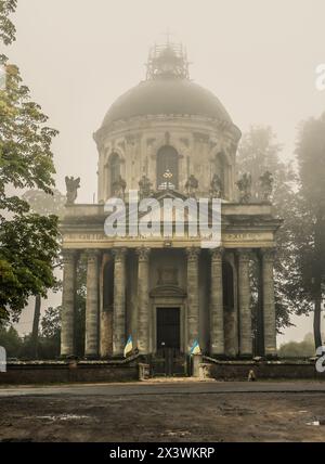 Nebelansicht der römisch-katholischen Kirche Exaltation of the Holy and St. Joseph in der Nähe des Dorfes Pidhirtsi, Lemberg, Ukraine. Alte Kirche am Hinterhof bei Sonnenaufgang Stockfoto