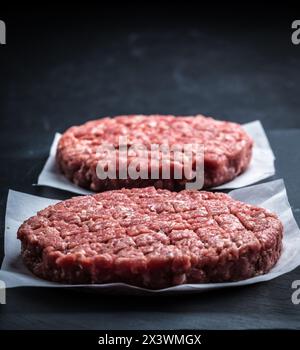 Rohes Hackfleisch-Burger-Schnitzel auf grauem Kochhintergrund Stockfoto