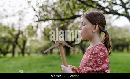 Mädchen, das draußen im Park steht und Windkraftanlage hält. Erneuerbare Windenergie und nachhaltige Lebensweise. Stockfoto