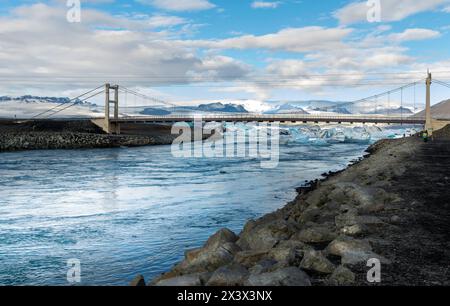 Eine Brücke überspannt einen Fluss mit Blick auf Eis und Schnee. Die Brücke hängt über dem Wasser und der Himmel ist klar Stockfoto