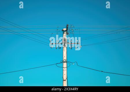 Strommast mit Oberleitungen und Straßenlaterne vor blauem Himmel Stockfoto